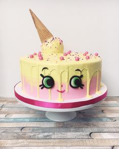 a cake with an ice cream cone on top and eyes painted on the side, sitting on a table