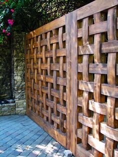 a wooden fence that is next to a brick wall with flowers growing on the side