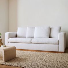 a white couch sitting on top of a wooden floor next to a vase filled with flowers