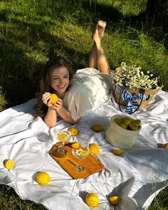 a woman laying on the grass with some lemons