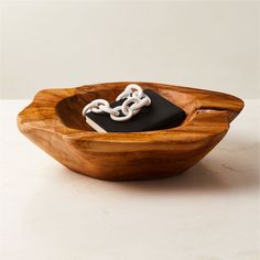 a wooden bowl with a black and white cell phone in the center, on top of it