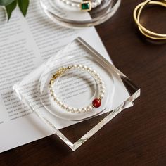 a pair of bracelets sitting on top of a wooden table next to a ring