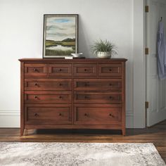 a wooden dresser sitting on top of a hard wood floor next to a white door