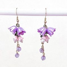 the earrings are purple and have flowers hanging from them