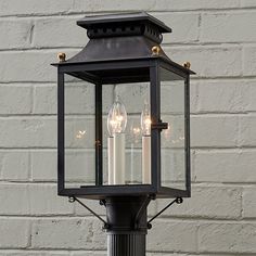 an old fashioned lantern with three lit candles in front of a brick wall