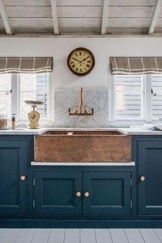 a kitchen with blue cabinets and a large clock on the wall above it's sink