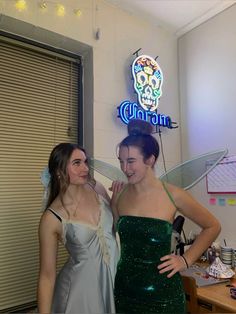 two women standing next to each other in front of a neon sign