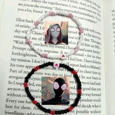 an open book with a spiderman necklace on it's side and two pictures of the same character