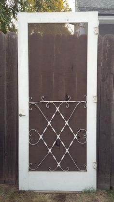 a cat sitting on the ground in front of a wooden door with wrought iron bars