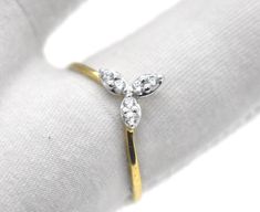 a gold and diamond ring sitting on top of a white cloth covered pillow with two diamonds in the middle