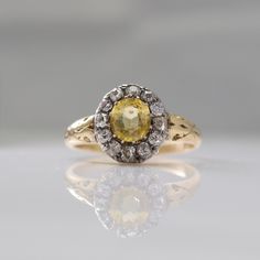 a yellow and white diamond ring sitting on top of a table