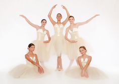 four ballerinas in tutus posing for a photo