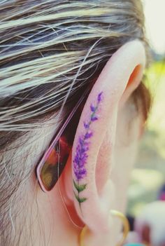 a close up of a person's ear with purple flowers on the back of their ears