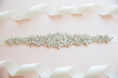 Adorn with delicate rhinestones this beautifully detailed sash is a must to complete your bridal look! The rhinestone embellishment measures about 11.5 inches long and 2 inches wide at the widest point. Finished with ivory satin ribbon, this sash ties sweetly with a bow. Please, select a ribbon color from drop down menu. Bridal Belts And Sashes, Bridal Belts, Wedding Belt, Bridal Party Robes, Bridesmaids Photos, Wedding Sash Belt, Wedding Robe, Wedding Sash, September Wedding