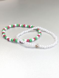 ♥ Adorable set of holiday-themed beaded bracelets. One bracelet is a small white pearl with a gold star bead. The other bracelet has red, white, and green glass seed beads.  ♥ Stack the bracelets or wear them separately.    ♥ They are made out of elastic cord and double-tied with adhesive reinforcement.  ♥ They make a great accessory to your holiday outfit or a great gift.   ::SIZE:: 7 inches   ::WOMEN'S BRACELET SIZES:: * Petite: 6 to 6.5 inches * Average: 7 to 7.5 inches * Plus size: 8 to 8.5 Festive Adjustable White Pearl Bracelet, Adjustable White Pearl Bracelet For Festive Occasions, Holiday White Beaded Jewelry, White Bracelets With Colorful Beads For Christmas, Festive White Beaded Bracelets With Colorful Beads, White Christmas Bracelets With Colorful Beads, Christmas White Bracelets With Colorful Beads, Holiday White Beaded Bracelets, White Adjustable Beaded Bracelets For Holidays