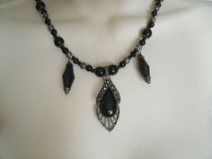 "This beautiful necklace has black czech glass beads, black pearl beads, sterling silver plated filigree beads, pewter silver accent beads, sterling silver plated bead caps, seed beads, black faceted drops, pewter silver pendant with black resin setting and Chinese crystals. 18\" long. Sterling silver plated toggle clasp."