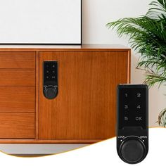 a wooden cabinet with an electronic door lock on it and a plant next to it