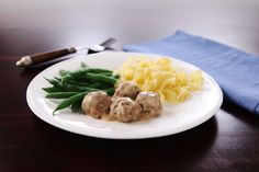 a white plate topped with meatballs and green beans