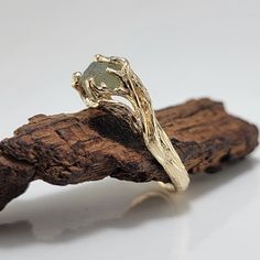 a gold ring sitting on top of a piece of driftwood next to a white background