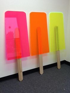 three popsicles are lined up against a wall with neon colored paint on them