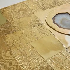 a close up of a toilet in a bathroom with gold tiles on the floor and walls