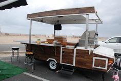 a food truck parked on the side of the road next to a white van and some stools