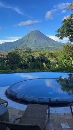 an outdoor swimming pool with chairs around it and a view of the volcano in the distance