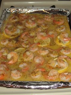 a pan filled with shrimp and lemons on top of a stove covered in tin foil