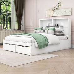 a white bed sitting in a bedroom next to a window with green pillows on top of it