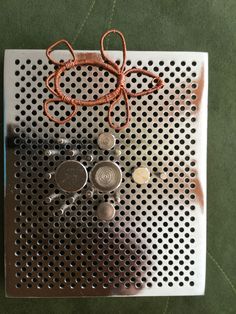 a piece of metal that has some coins on it and an orange string attached to it