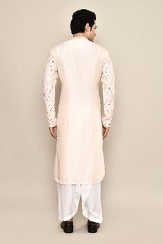 Blush cream kurta featuring mirror embroidery in the front and sleeves. Paired with a white salwar. - Aza Fashions White Embroidered Sleeves Straight Kurta, Festive White Kurta With Embroidered Sleeves, White Chanderi Sherwani With Mirror Work, White Embroidered Unstitched Kurta, White Kurta With Embroidered Sleeves, Chanderi Traditional Wear With Embroidered Sleeves For Wedding, Wedding Traditional Wear With Embroidered Sleeves In Chanderi, Wedding Traditional Wear With Embroidered Sleeves, Eid White Kurta With Embroidered Sleeves