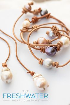 the freshwater pearl company logo is displayed on a white surface with brown cord and beads