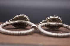 Silver ear ornaments. The hoops are made of pearled wire and the bezel is decorated with Turquoise. Excellent workmanship with a great patina for its age. This particular design is worn in pairs by women from Kham in East Tibet. These pieces might have been handed down to generations. *wear and tear as per age, intact. Weight: 28 grams Ring Size: 34mm Origin: Early 20th c Tibet Vintage Round Hoop Earrings With Intricate Design, Traditional Adjustable Hoop Jewelry, Traditional Oxidized Finish Earrings, Traditional Earrings With Oxidized Finish, Traditional Earrings With Oxidized Finish And Adjustable, Traditional Adjustable Spiral Jewelry, Traditional Spiral Silver Jewelry, Traditional Silver Spiral Jewelry, Traditional Handmade Spiral Jewelry