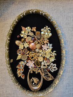 a black and gold brooch with flowers in the center on a gray cloth background