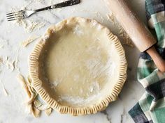 an uncooked pie sitting on top of a table next to utensils