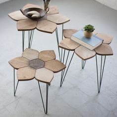 three wooden tables with metal legs and flower design on each table, one has a potted plant in the middle