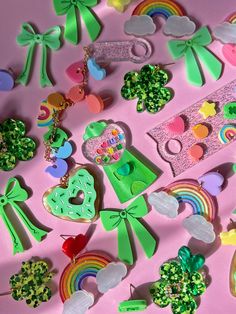 many different types of brooches and accessories on a pink surface with rainbows