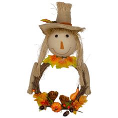 a scarecrow head hanging on a wall with leaves and acorns around it