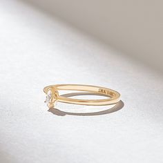 a yellow gold ring with a single diamond on the side, sitting on a white surface