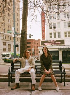 two women sitting on a bench in the city