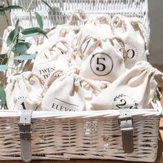 a white basket filled with lots of laundry bags next to a potted plant on top of a wooden table