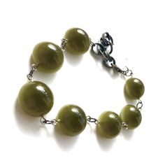 Olive green in a rich deep tone & subtle moonglow in the shape of rounded flat backs, meet gritty gun metal chain in this adjustable to 8.5" Stations Bracelet. Enough of a statement to be worn on it's own OR stack for an arm party with others. Lots of versatility from 6.5 to 8.5" and swivel lobster claw makes it so that you can latch a link all by yourself. Light weight with a chunky look. Because the beads we use are vintage & sometimes very limited, beads may vary slightly from the des Green Bracelet With Adjustable Chain, Green Bracelets With Adjustable Chain, Adjustable Green Metal Bracelets, Trendy Green Metal Bracelets, Surgical Steel Earrings, Arm Party, Rainbow High, Moon Glow, Vintage Lucite