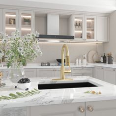 a white kitchen with marble counter tops and gold faucet