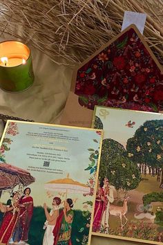 there are cards with pictures on them next to a lit candle and some straw grass