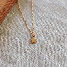 I love stars and this Gold Star Necklace is a charmer. Stars celebrate accomplishments, promote inner confidence to be your best, and are reminders of beautiful starry nights. This dainty mini star can be on a 16 inch or 18 inch 14K gold filled chain. Bronze star measures 1/4” wide and hangs 1/2” from chain 14K gold filled chain is 16 inch or 18 inch, Lead and Nickel Free. Assembled in our studio in Portland, OR Dainty Yellow Gold Star Charm Necklace, Dainty 14k Gold Filled Star Charm Necklaces, Dainty 14k Gold Filled Star Charm Necklace, Delicate Yellow Gold Star Charm Necklace, Delicate Yellow Gold Charm Necklace With Star Charm, Dainty Star Charm Necklaces, Dainty Star Of David Charm Necklace With Delicate Chain, Dainty Star Charm Necklace, Dainty Star-shaped Charm Necklace