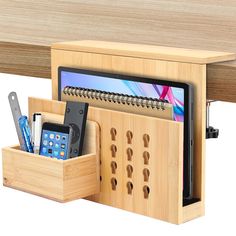 a wooden desk with a cell phone, pencils and an ipad in the holder