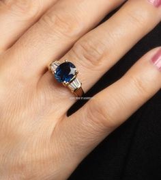 Sapphire engagement ring, Blue sapphire ring, Side Tapper diamond ring, Art Deco Ring, Blue Gemstone Statement Ring, Anniversary Gift Ring ✦ CENTER STONE DETAIL ✦ ✧ Stone Type : Lab Created ✧ Stone Shape : Oval ✧ Stone Size : 9x7 MM ✧ Stone Color : Blue Sapphire ✧ Stone Clarity: Si ✧ Luster: Excellent ✧ Make: High-Quality Craftsmanship ✦ SIDE STONE DETAIL ✦ ✧ Stone Type : Simulated Diamond ✧ Stone Shape : Tapper Baguette ✧ Stone Color : D (White High brilliant) ✧ Stone Clarity : VVS ✧ Luster: Excellent ENGRAVING IS AVAILABLE ✦ 𝐌𝐞𝐭𝐚𝐥 𝐃𝐞𝐭𝐚𝐢𝐥𝐬 ✦ ✧ Metal Type: Solid Gold , 925 Silver ✧ Metal Purity: 10K | 14K | 18K | 925 Silver ✧ Metal Tone: Rose | White | Yellow ( Selict Option in Material ) This ring can be customized by the moissanite(E-F color, VVS clarity)center Stone,please c Gia Certified Diamond Sapphire Ring, Gia Certified Blue Topaz Ring With Diamond, Gia Certified Blue Topaz Diamond Ring, Gia Certified Sapphire Ring, Classic Blue Sapphire Ring With Diamond Accents, Blue Diamond Ring With Vvs Clarity, Blue Diamond Ring With Round Cut, Blue Sapphire Rings With Diamond Accents, Gia Certified Baguette Cut Sapphire Ring