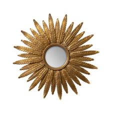 a gold sunflower mirror hanging on the wall next to it's own reflection