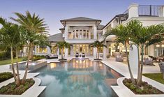 an outdoor pool surrounded by palm trees in front of a house