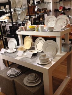 a table with plates and bowls on it in a room filled with shelves full of dishes